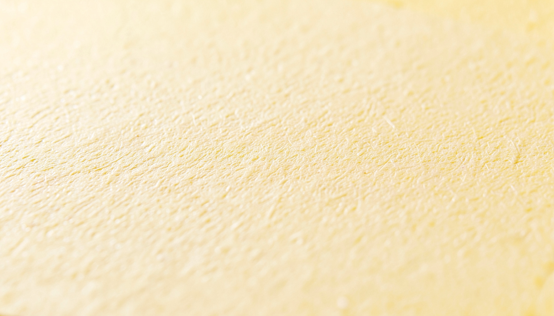 Close-up of matte paper with fine fiber texture, warm cream tone, soft natural lighting