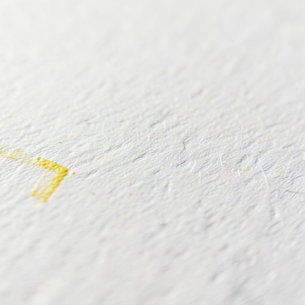 Close-up of a textured matte paper surface with subtle fiber weave, soft off-white tone